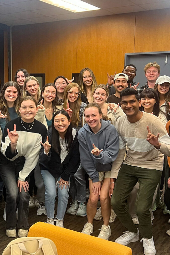 Group photo of students smiling and doing the Hook em Horns hand signal